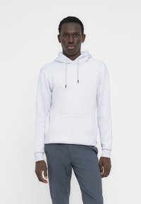 Ανοιχτό γκρι φούτερ με κουκούλα από μαλακό ύφασμα, με τσέπη μπροστά, ρυθμιζόμενη κουκούλα με κορδόνι και ριμπ μανσέτες. Συνδυασμένο με σκούρο γκρι παντελόνι.