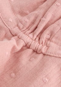 Helle rosa Leinenstoff mit strukturierten Punkten und gerafften elastischen Details, der weiches, atmungsaktives Material in einem glatten Finish präsentiert.