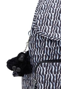 Mochila con un patrón ondulado en negro y azul claro, con un llavero de gorila negro de peluche adjunto. Se ve un bolsillo con cremallera.