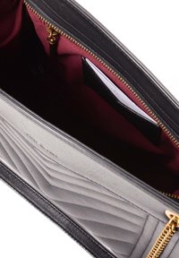 Black leather handbag with a quilted design, gold zipper, and a deep maroon interior lining featuring card slots. Compact and structured shape.