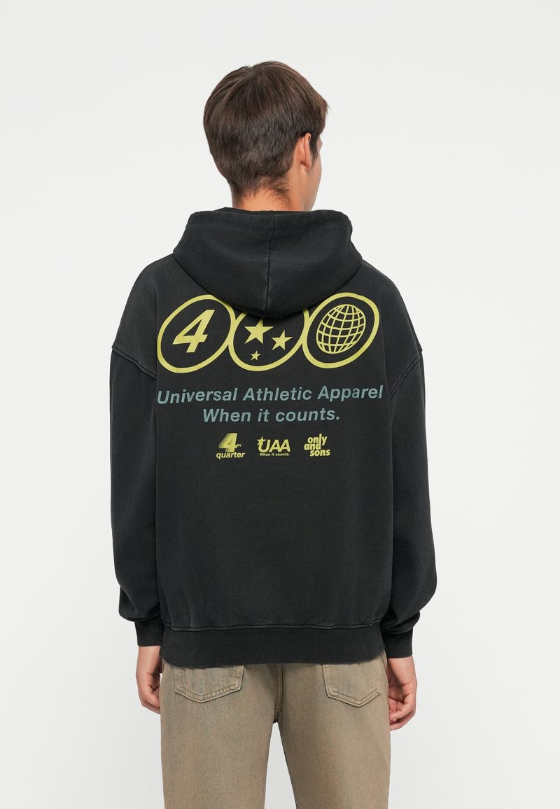 Sweat à capuche noir avec un grand motif jaune au dos, comprenant des icônes circulaires et du texte. Confectionné dans un tissu doux, il présente une coupe décontractée et une capuche.