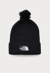 Svart strikket vinterlue med pom-pom og brettet kant som har et rektangulært merkelapplogo med teksten "The North Face."