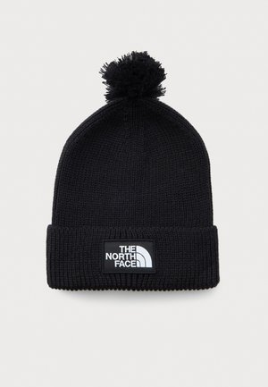 Svart strikket vinterlue med pom-pom og brettet kant som har et rektangulært merkelapplogo med teksten "The North Face."