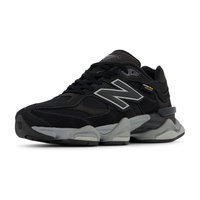 Baskets en daim noir et mesh avec des accents gris, présentant une semelle épaisse, un système de laçage et un logo "N" bien en évidence sur le côté.