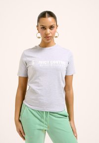 Pilkas trumpomis rankovėmis marškinėliai su užrašu „JUICY COUTURE“ ir „Sunday Running Club“ baltomis raidėmis. Minkšta medžiaga, laisvas kirpimas. Sutampama su mėtos žalios spalvos kelnių.