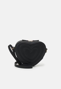 Czarna torebka crossbody w kształcie serca z wytłoczonymi sercami i regulowanym paskiem na białym tle.