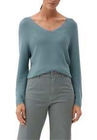 Suéter de punto azul apagado con escote en V y mangas largas, combinado con pantalones de talle alto en gris claro.