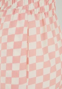 Pink and white checkered fabric with elastic waistband and a vertical slit pocket on a garment.