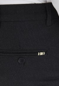 Svarta tygbyxor med knäppning, framficka med randig accent och en slät yta.