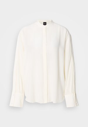Blouse à manches longues crème en tissu lisse ; col mao, patte de boutonnage à l'avant, poignets boutonnés et coupe décontractée.