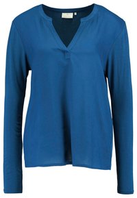 Långärmad blå topp med V-ringning och plackdetalj; mjukt tyg med en slät yta och lätt rundad fåll.