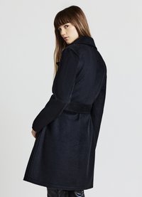 Cappotto lungo in misto lana nera con colletto, vita con cintura e tasche laterali, caratterizzato da una texture liscia e una silhouette al ginocchio.