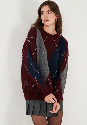 Maglione oversize a motivo argyle nei colori bordeaux, grigio e blu navy con polsini a coste. Presenta un colletto a girocollo e una morbida texture in maglina.