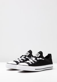 Černé plátěné tenisky s bílým šněrováním, gumovou špičkou a bílou podrážkou s dvěma černými pruhy. Prodyšná síťovina.