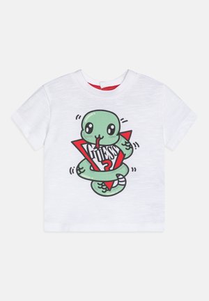 Maglietta bianca per bambino con un serpente verde disegnato avvolto intorno a un triangolo rosso e la parola "GUESS" in lettere nere all'interno del triangolo.