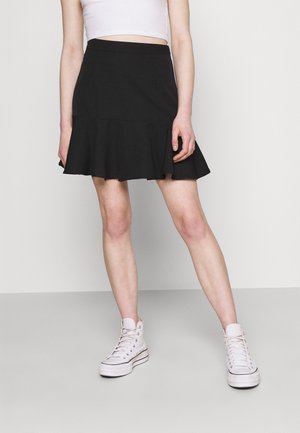 Schwarzer ausgestellter Rock mit tailliertem Bund, aus weichem Stoff. Kombiniert mit weißen High-Top-Sneakers für einen lässigen Look.