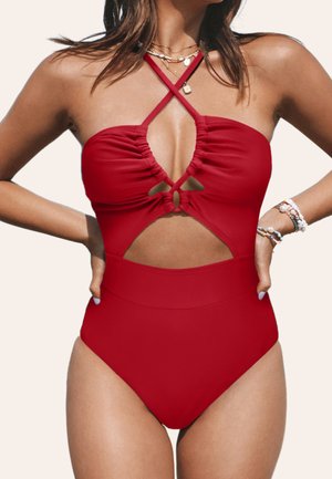 Costume da bagno intero rosso con busto arricciato, lati ritagliati e spalline incrociate. Presenta una vita alta e un dettaglio a chiave al centro.