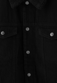 Veste en denim noir, vue de face, avec col en polaire, boutons-pression métalliques, et deux poches poitrine à rabat avec fermetures à pression.