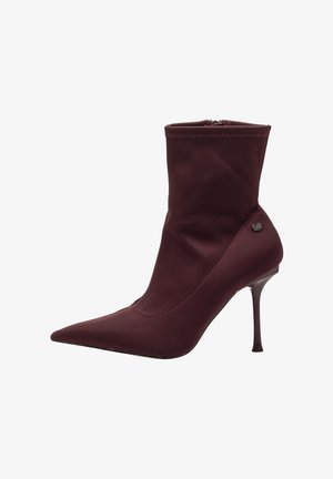 Botín burgundy de tela elástica con punta afilada, tacón de aguja delgado y costuras decorativas a lo largo del borde superior.