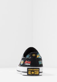 Schwarze Leinensneaker mit mehrfarbigen Batman-Motiven, ausgestattet mit einer Gummisohle und Converse All Star-Branding an der Ferse.