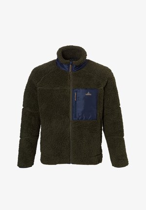 Mann trägt dunkelgrüne Fleecejacke mit navyblauer Brusttasche und navyblauen Shorts, lächelnd und vor weißem Hintergrund stehend.