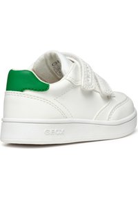 Baskets blanches avec une finition texturée, un accent en cuir vert au niveau du talon et des brides Velcro. Elles possèdent une semelle en caoutchouc blanc solide.