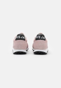 Baskets en suede rose avec une semelle blanche et un talon noir portant le logo "VEJA". Forme arrondie, finition texturée et semelle en caoutchouc antidérapante.