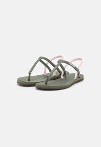 Green rubber sandals with pink straps. Flat sole with a textured surface. Minimalist design featuring a thong style and subtle logo detail.