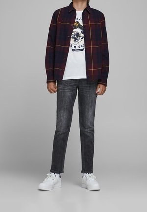 Sininen ja viininpunainen ruudullinen nappipaita valkoisen graafisen t-paidan päällä, yhdistetty kapeisiin harmaisiin farkkuihin ja valkoisiin tennareihin.