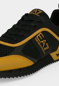 Μαύρο και κίτρινο αθλητικό παπούτσι EA Emporio Armani με μαύρα κορδόνια, διχτυωτές επιφάνειες και λεπτομέρεια σε υφή σόλας.