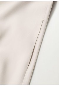 Beige tkanina s hladkým povrchem a jemným leskem. Obsahuje boční rozparek pro designový detail, který zdůrazňuje čistý a upravený vzhled.
