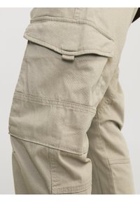 Beige cargobyxor med ett texturerat, hållbart tyg. Har flera fickor och förstärkt sömnad för ökad styrka och funktionalitet.