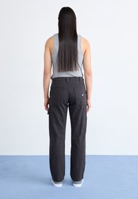 Svarta cargobyxor med smala ränder, flera fickor, rak passform och hög midja, tillsammans med en grå linne.