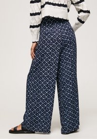 Spodnie o szerokich nogawkach w granatowym kolorze z geometrycznym wzorem w jasnoniebieskim odcieniu, gładką fakturą i elastycznym pasem dla wygody.