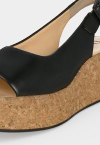 Μαύρο δερμάτινο σανδάλι πλατφόρμα με ανοιχτό δάχτυλο, ρυθμιζόμενο λουράκι και χοντρή φαρδιά φελλόσολα, με πλευρική και μερική πάνω όψη.