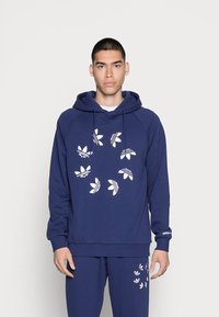 Mørkeblå hættetrøje med et hvidt blomstermønster og logo. Har snoretræk i huen, raglanærmer og ribbede manchetter og kant.