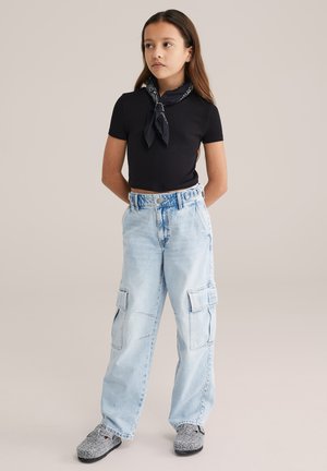 Melna cropped t-krekls, gaiši zili cargo stila bikses ar sānu kabatām un melni balti rakstainas slip-on kurpes. Vienkāršs, ikdienišķs apģērbs.