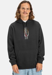 Sudadera con capucha negra hecha de una mezcla de algodón, con un logo central que presenta gráficos de llamas en rojo, naranja y blanco. Incluye bolsillo frontal.