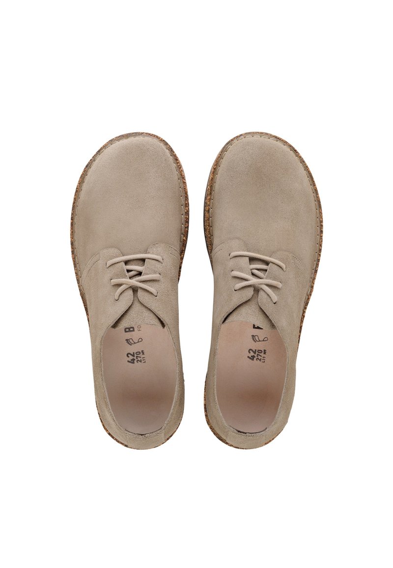 Beige mockaskor med snörning, rundad tå, texturerad yta och sula som liknar kork. Har en minimalistisk design och platta snören.