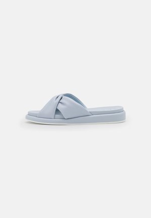 Sandale slide bleu clair avec une semelle rembourrée et une large bride torsadée sur le dessus, vue de profil sur un fond uni.