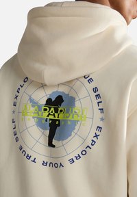 Felpa color crema con un grafiche circolare. Il design include un globo blu e una silhouette nera, con "NAPAPIJRI geographic" in verde.