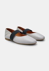 Scarpe flat in pelle bianca con una fascia elastica nera sul collo del piede, con punta affusolata e suola bassa marrone.