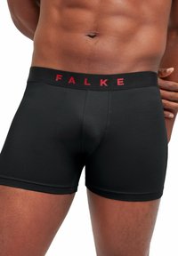 Boxer shorts noirs au fit ajusté, dotés d'une large ceinture élastique noire avec l'inscription rouge "FALKE". Texture lisse, courte longueur.