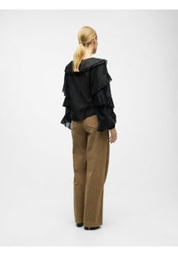 Zwarte geplooide blouse met een capuchon en poefmouwen, gecombineerd met hoge, geribbelde bruine corduroy broeken, beide met een relaxte pasvorm.