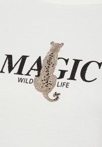 Weißes T-Shirt mit einem Leoparden-Motiv in Braun mit schwarzen Flecken, begleitet von dem Text "MAGIC WILDLIFE" in fetten schwarzen Buchstaben.