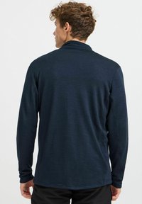 Langarmshirt in Marineblau, ausgestattet mit einem strukturierten Stoff und einer lässigen Passform. Das Design beinhaltet einen klassischen Kragen und einen leicht abgerundeten Saum.