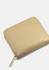 Beige leren portefeuille met een textuurovervlak, gouden rits en reliëflogo. Beschikt over afgeronde hoeken en stiknaad.