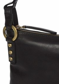 Bolsa de cuero negro con un anillo de latón y tirador de cremallera, con tres tachuelas decorativas en el costado. Textura suave con forma estructurada.