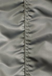 Close-up of gray fabric with a central vertical seam and slight gathering creating soft folds on either side.