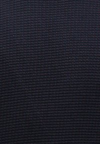 Υφαντό ναυαρίνο ύφασμα με υφή εμφανίζει ένα πλέγμα με διακριτές αποχρώσεις του κόκκινου. Το υλικό φαίνεται να είναι υφασμένο, προσφέροντας μια αφής, δομημένη επιφάνεια.